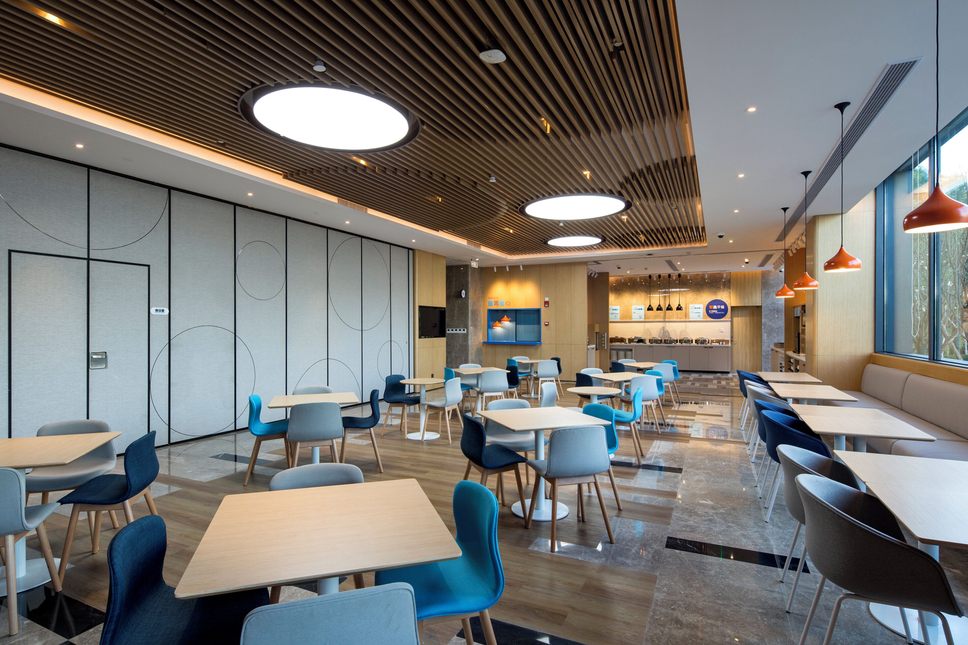 A modern restaurant with multiple tables and chairs, a kitchen area, and a seating area with a view.