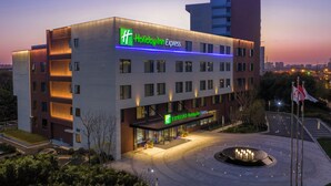 Ein Holiday Inn Express Hotel mit modernem Design, inklusive auffälligem Schild, gut beleuchtetem Eingangsbereich und einem angelegten Innenhof.