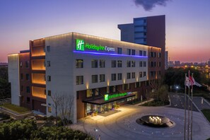 Een Holiday Inn Express hotel met een modern ontwerp, met een opvallend bord, een goed verlichte ingang en een aangelegde binnentuin.
