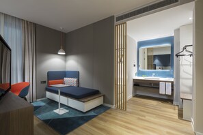 A modern hotel room with a bed, a desk, a chair, a bathroom with a mirror, and a sink. - Holiday Inn Express Shanghai Kangqiao by IHG (Shanghai)