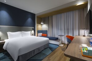 A modern hotel room with a large bed, a desk with a chair, a television, and a window with curtains. - Holiday Inn Express Shanghai Kangqiao by IHG (Shanghai)