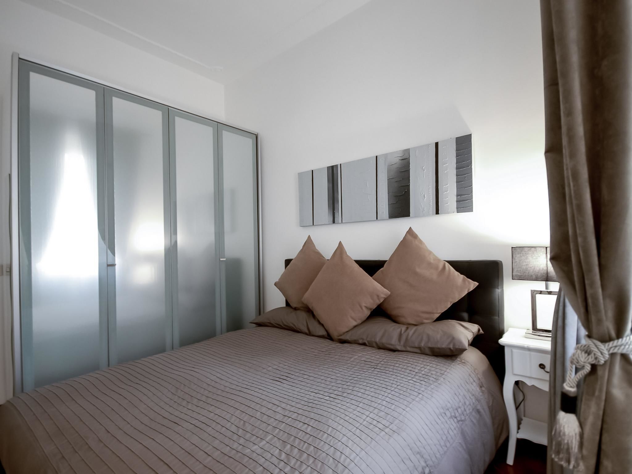 Un dormitorio con cama, armario, mesita de noche y lámpara.