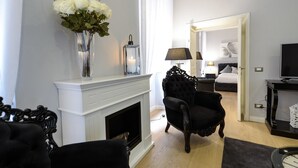 A modern living room with a fireplace, a black armchair, and a television. - Belsiana Apartment (Rome)