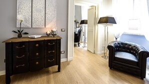 A room with a dark wooden dresser, a black leather sofa, and a white door leading to another room. - Belsiana Apartment (Rome)