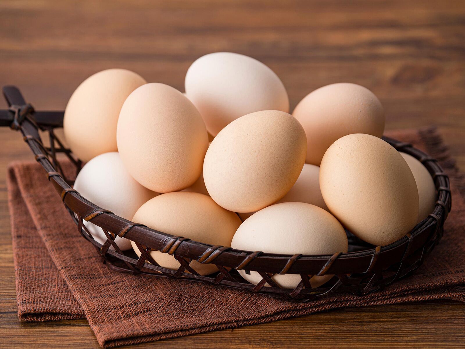 A basket of eggs on a wooden surface.