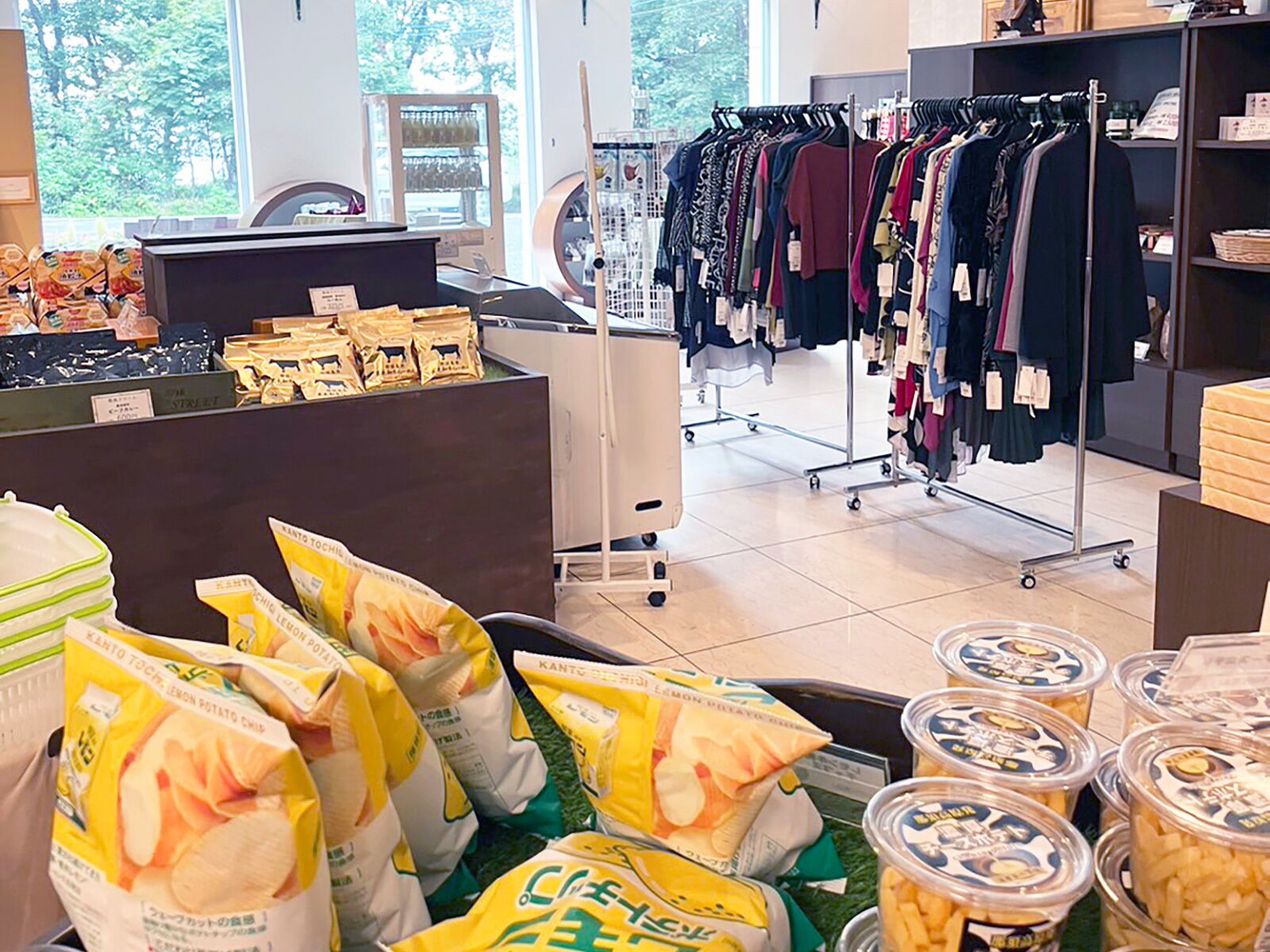 A retail store with a clothing rack, a vending machine, and bags of lemon potato chips.