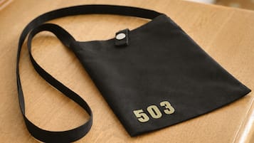 Eine schwarze Tragetasche mit der Nummer 503, platziert auf einer Holzfläche.