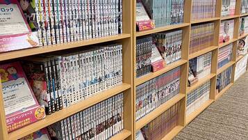 A library with bookshelves filled with manga and anime series.