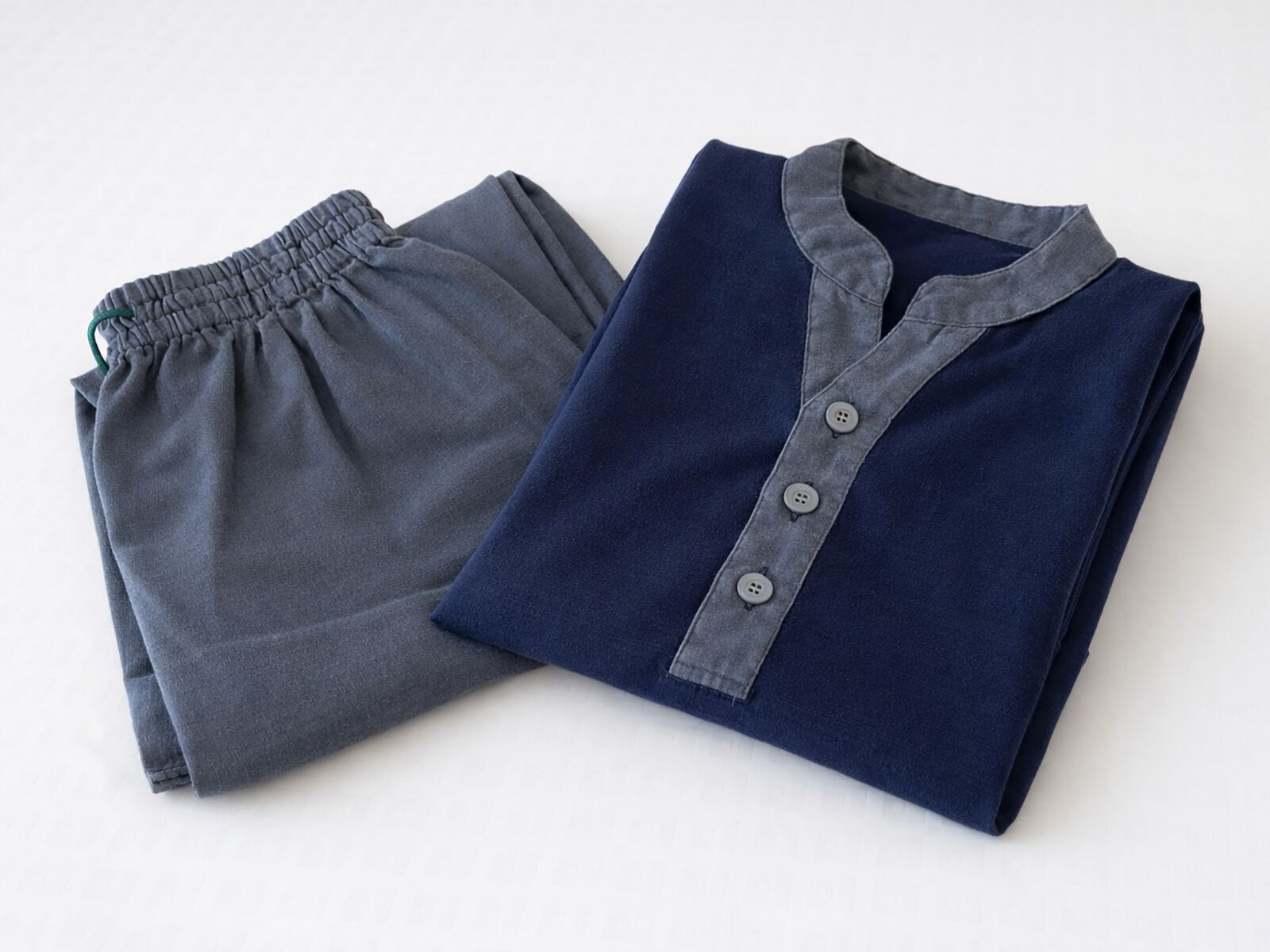 Due capi di abbigliamento piegati, uno grigio e uno blu navy, con colletto e bottoni su quest'ultimo.