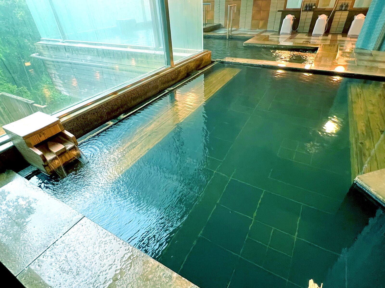 An indoor swimming pool with a wooden bench and a tiled floor.