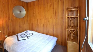 A room with wooden walls, a bed with a white quilt, a round wall light, and a wooden ladder. - Rustic apartment in Courchevel, near slopes (Courchevel 1850)
