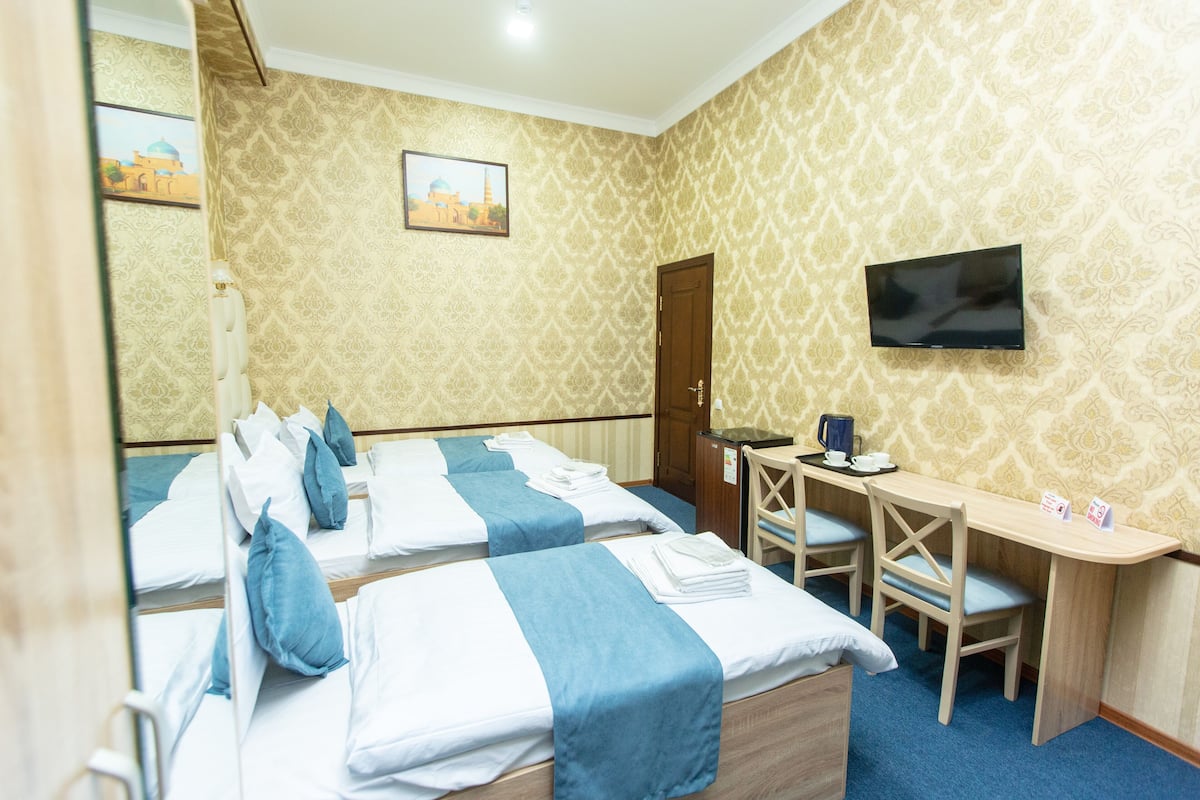 Une chambre d’hôtel avec deux lits, un bureau, une chaise, une télévision et une porte.