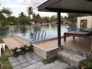 Zona de piscina con terraza de piedra, sillas de descanso y plantas en macetas.