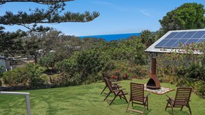 Un giardino sul retro con zona barbecue, posti a sedere all'aperto e un impianto di pannelli solari.