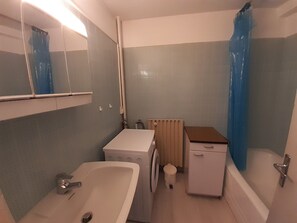 A small bathroom with a sink, a washing machine, a toilet, and a bathtub. - Ski-In Studio with Parking in Courchevel (Courchevel 1650)