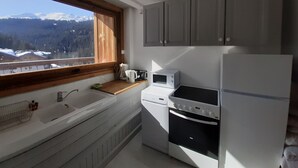Eine Küche mit Blick auf Berge, inklusive Spüle, Mikrowelle, Herd und Schränke.