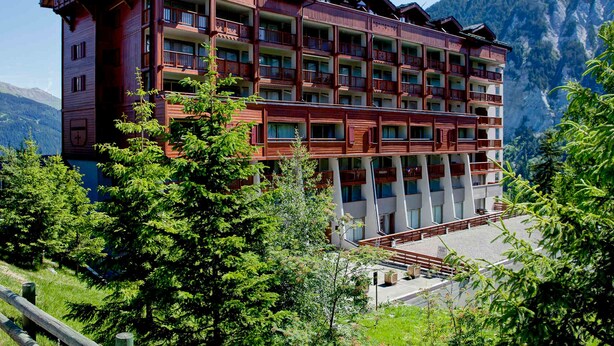 A multi-story hotel with balconies, set against a mountainous backdrop. - Charming apartment in Courchevel 1650 with parking (Courchevel 1650)