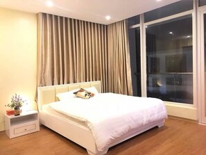 Relax in a spacious room with a large bed, bedside table, and city view.