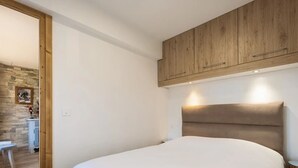 A bedroom with a wooden headboard, a white bedspread, and a small bedside table. - 3* Apartment, sleeps 6, pets allowed, garage, mountain view (La Clusaz)