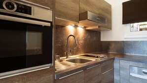 A modern kitchen with a built-in oven, stainless steel sink, and wooden cabinets. - 3* Apartment, sleeps 6, pets allowed, garage, mountain view (La Clusaz)