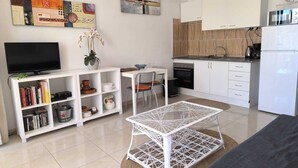 Un salon moderne avec un téléviseur à écran plat, une bibliothèque, une table basse blanche et un canapé.