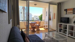 Un salon avec un canapé, une table basse en verre, un téléviseur et une bibliothèque.