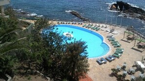 Une piscine à bords incurvés, entourée de chaises longues et offrant une vue sur la mer.