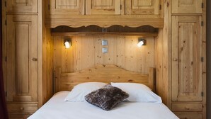 Un letto in legno con testiera, due lampade ai comodini e una piccola cassettiera.