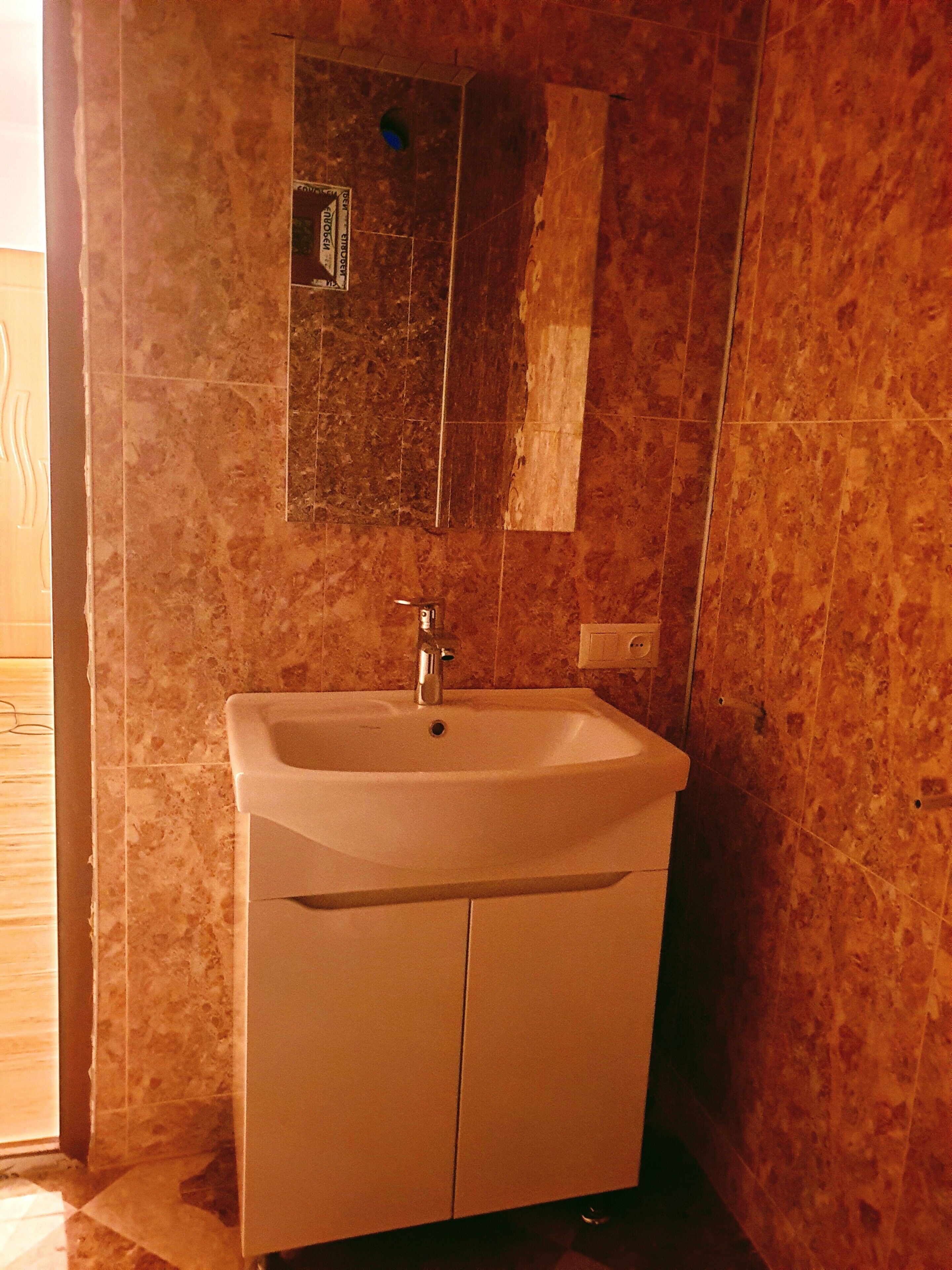 A bathroom with a sink, mirror, and tiled walls.