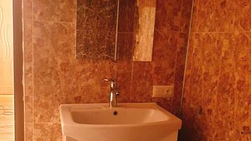 A bathroom with a sink, mirror, and tiled walls.