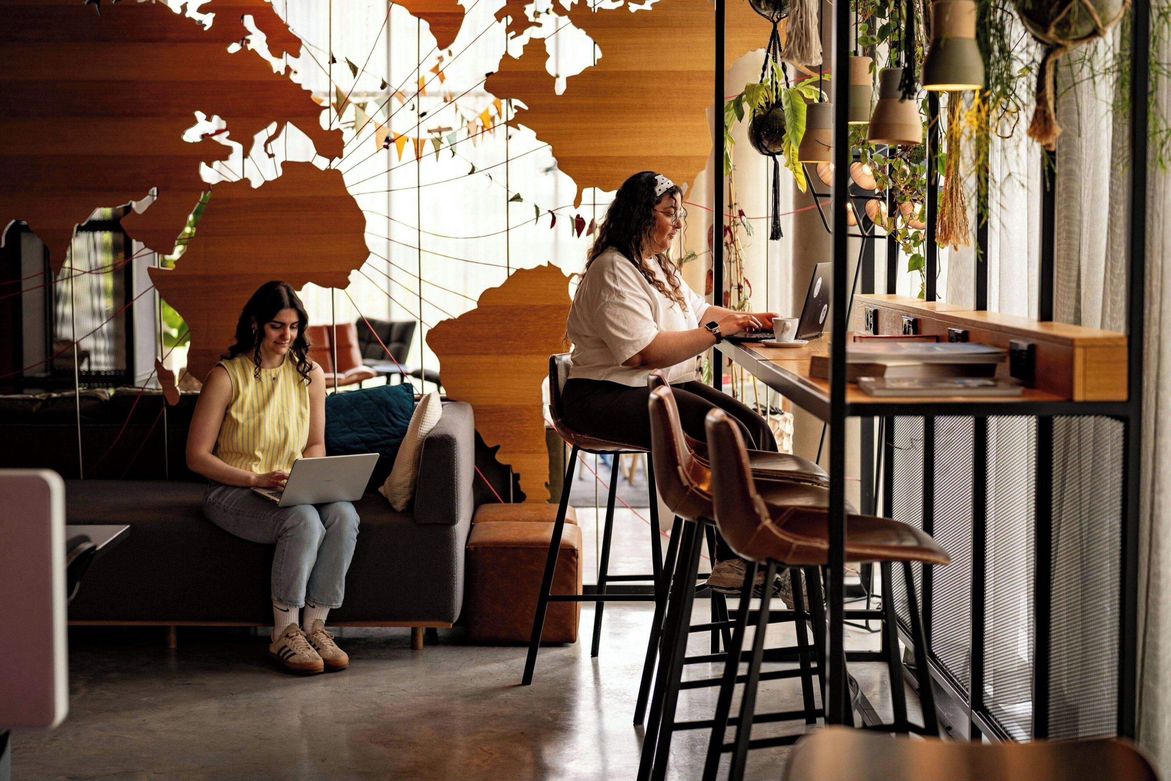Ein modernes Interieur mit einer Wandweltkarte, einem Sofa, einem Essbereich und einem Laptop.