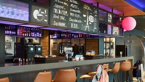 A bar area with a chalkboard menu, bar stools, and a variety of bottles.