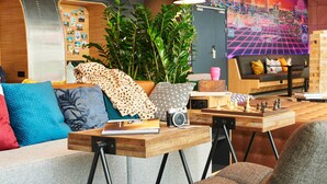 A cozy, modern lounge area with a sofa, a wooden table, and a chessboard.