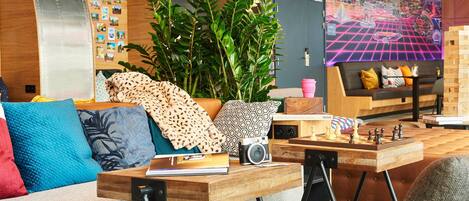 A cozy, modern lounge area with a sofa, a wooden table, and a chessboard.