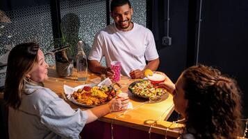 A group of people dining at a restaurant with a tiled wall and string lights in the background.