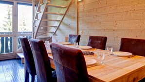 A dining area with a wooden table, six chairs, and a staircase.