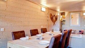 A wooden interior with a dining table set for four, surrounded by leather chairs.