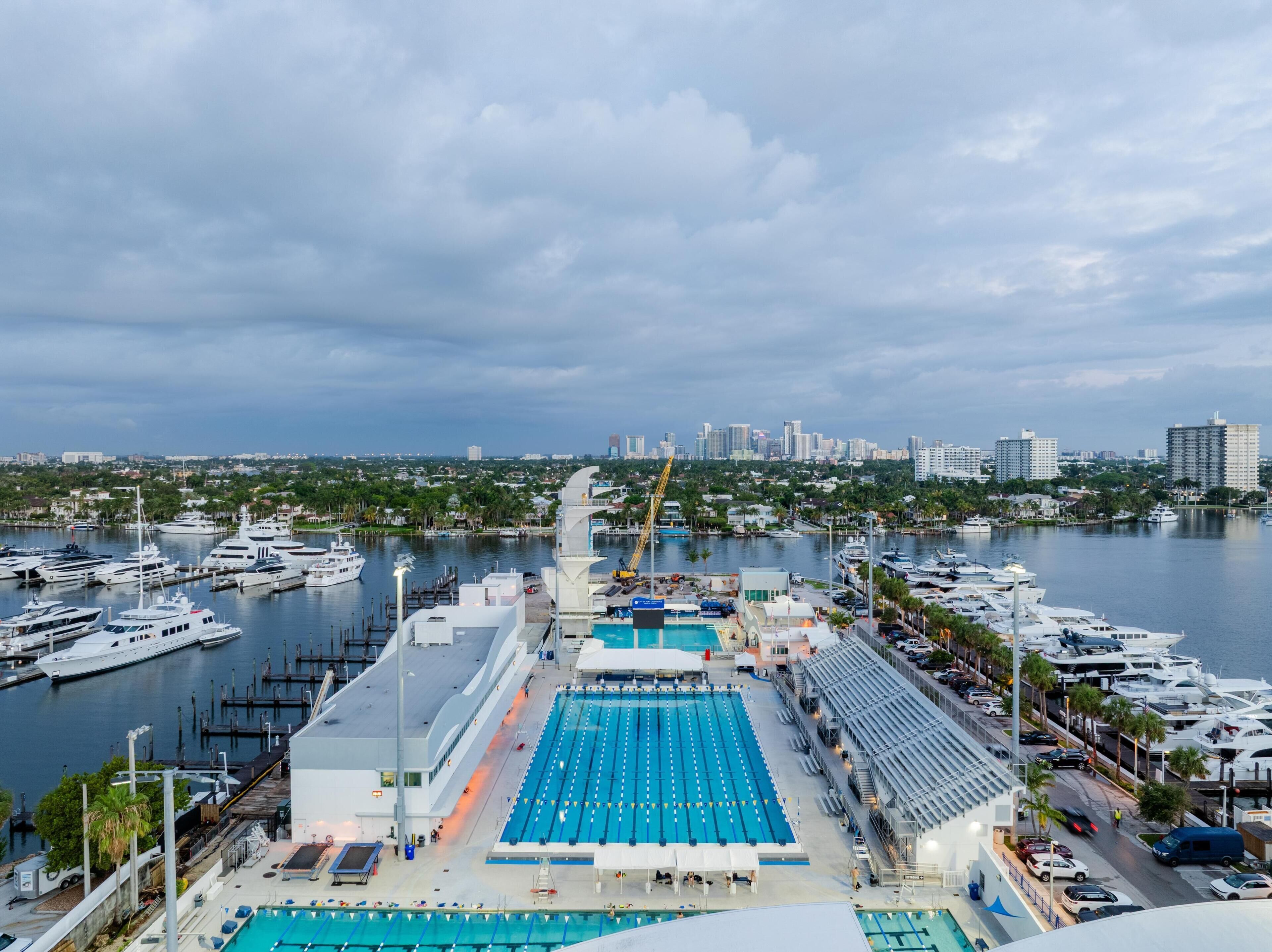 Un port de plaisance où sont amarrés de nombreux yachts, une piscine et, en arrière-plan, le panorama de la ville.