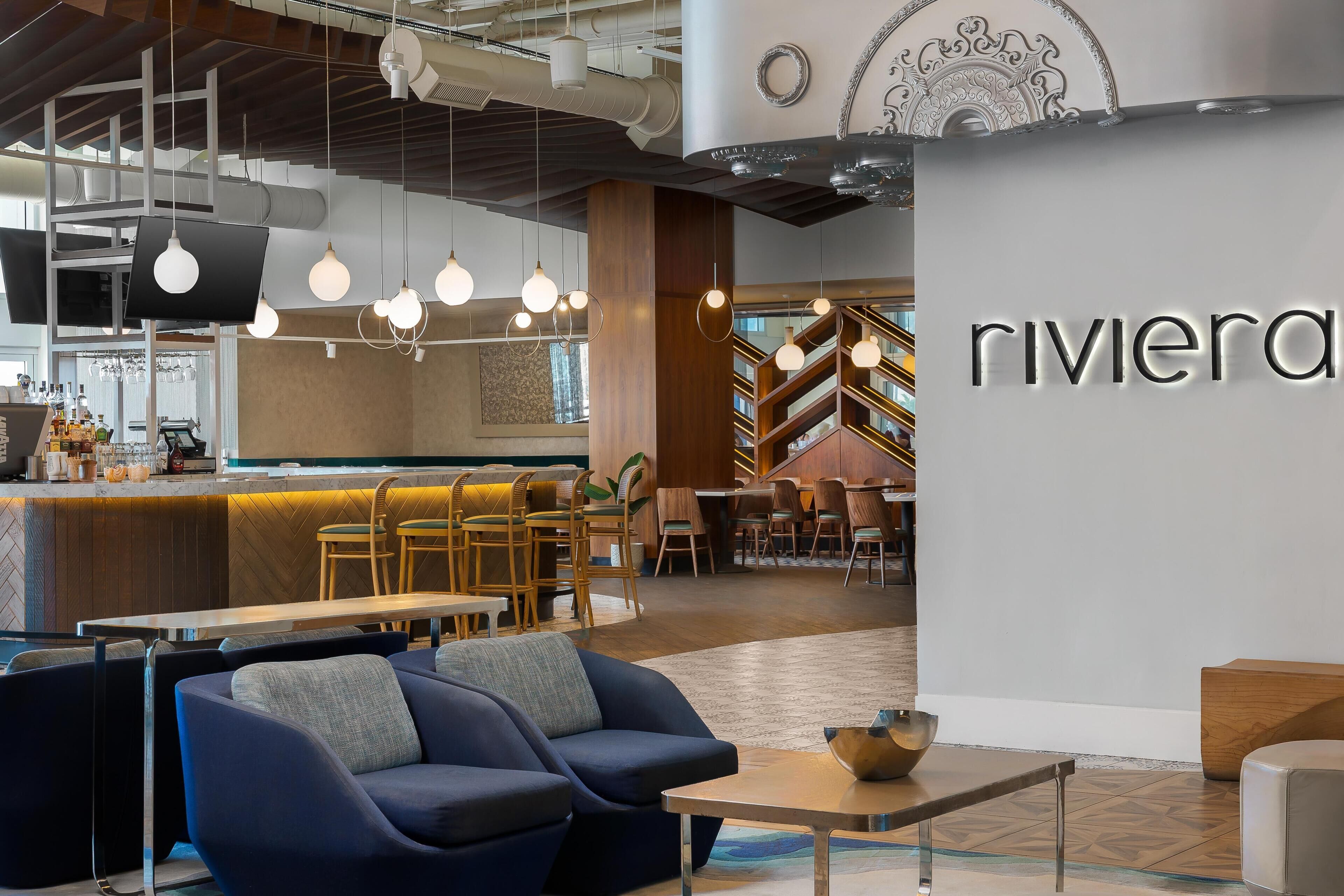 A modern interior with a bar area, seating, and a prominent 'riviera' sign.