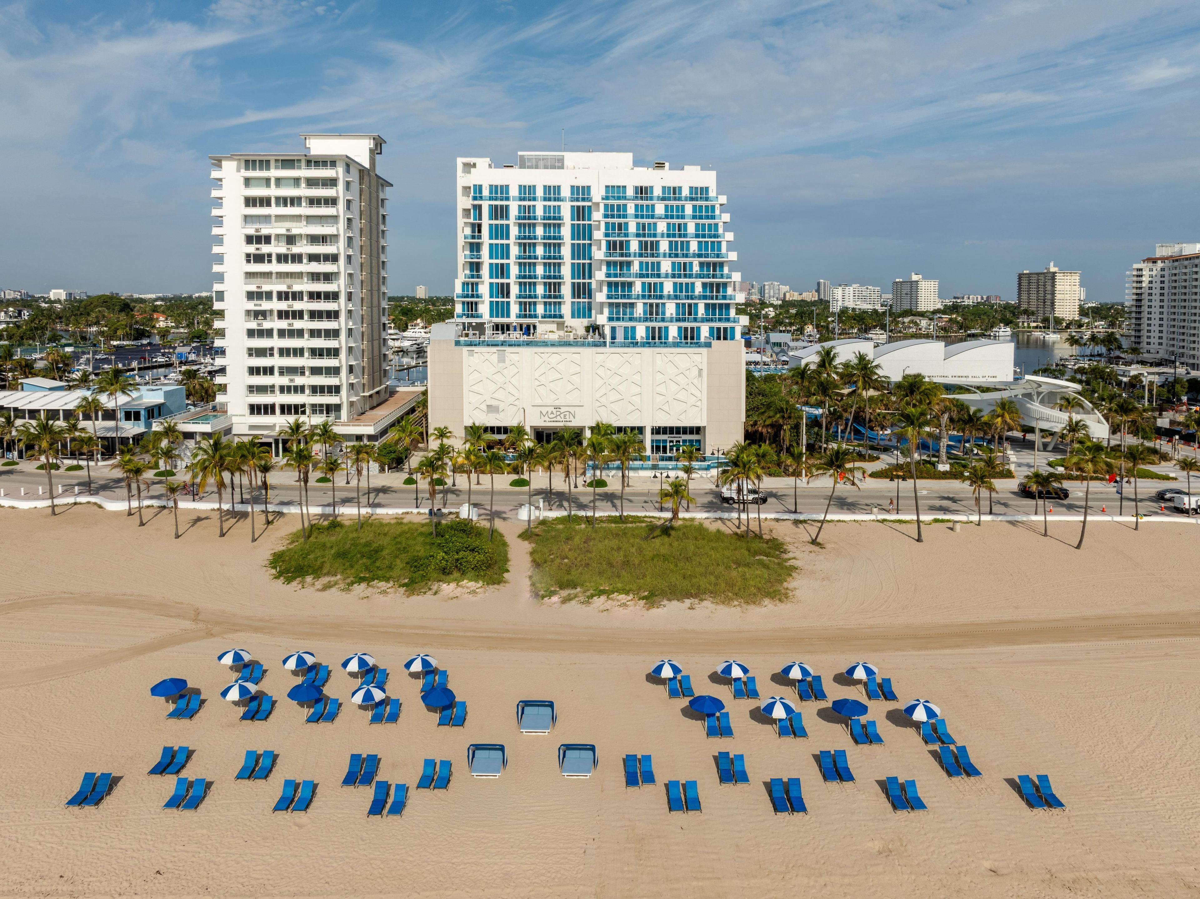 A beachfront hotel with multiple floors, a pool area, and beachside lounge chairs.