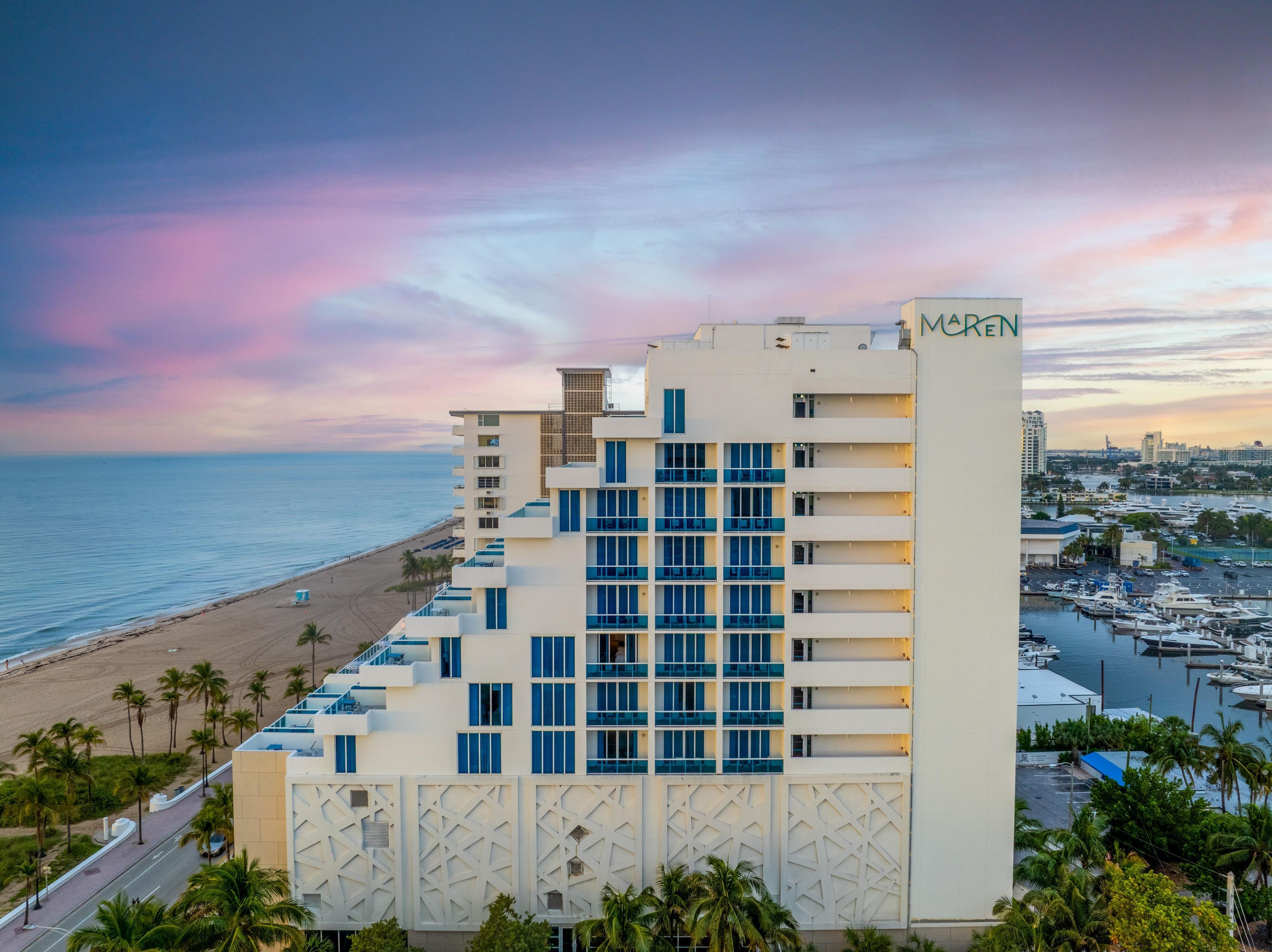Un hôtel avec vue sur la plage et le port de plaisance.