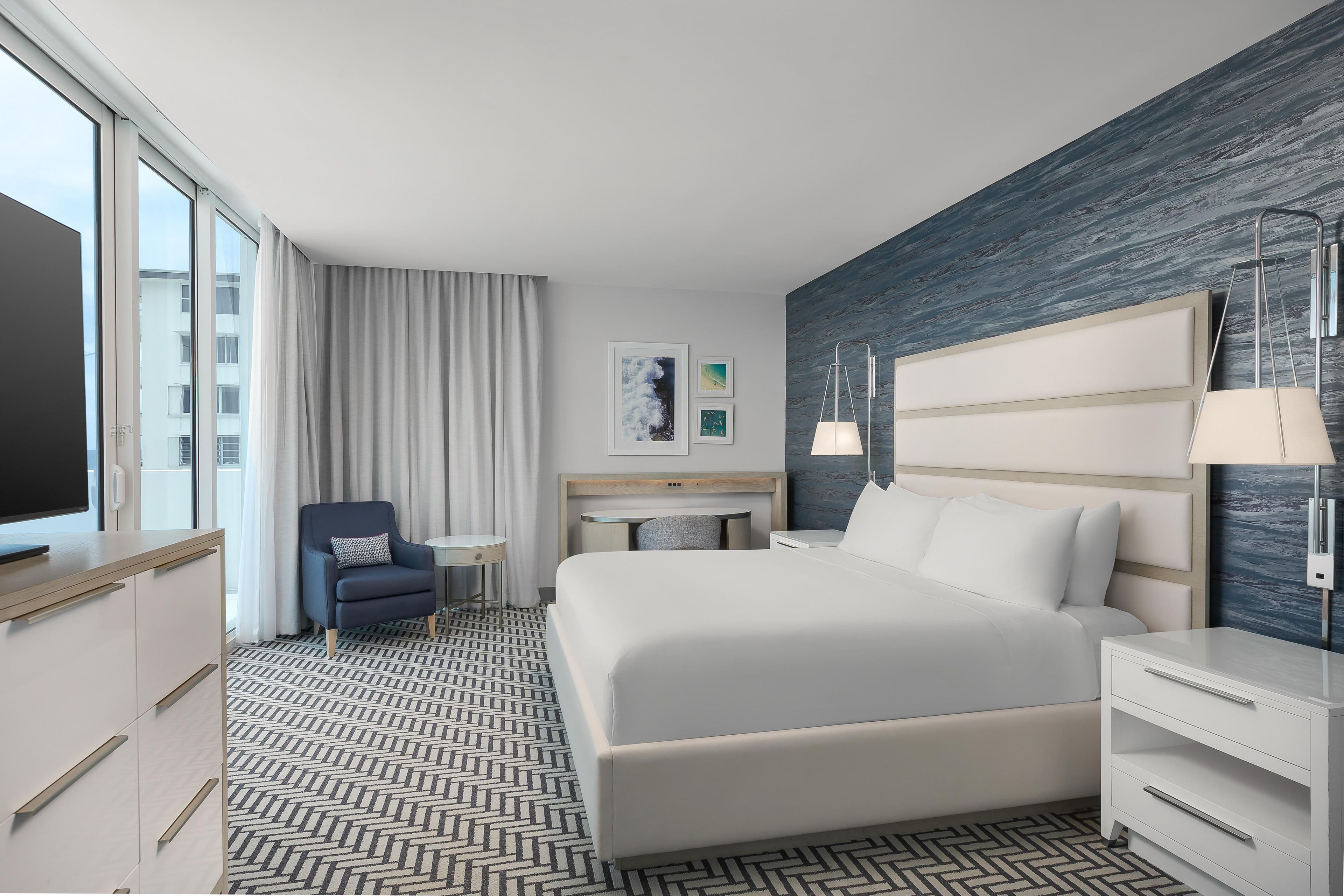 Une chambre d’hôtel avec un grand lit, un bureau, une chaise, une télévision et une vue sur la ville.