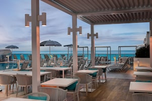 Zona de piscina con sillones y mesas, con vista al mar.