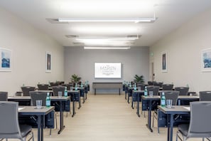 Une salle de conférence avec une longue table, des chaises et un écran affichant la mention « HÔTEL MAREN ST. LAURENT BEACH CURID COLLECTION ».