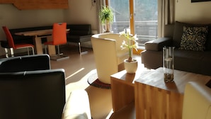 Una sala de estar moderna con una mesa de madera, un sofá y una zona de comedor con una silla roja.