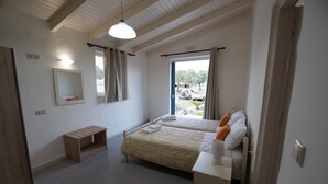 A bedroom with two beds, a wooden nightstand, a bedside table, a mirror, and a window with curtains. - Electra Studios (Platanias)