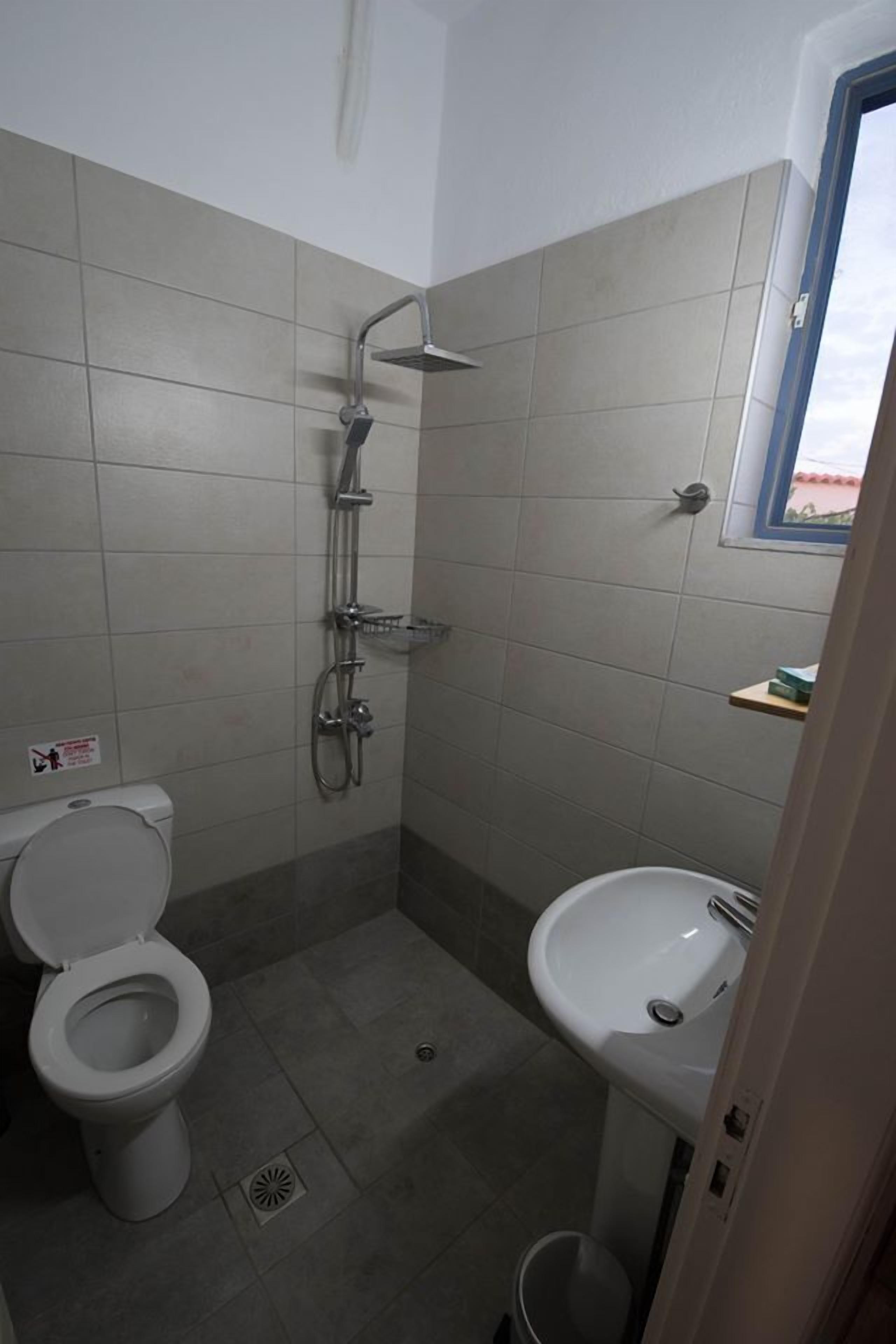 Un baño pequeño con inodoro, lavamanos y ducha.