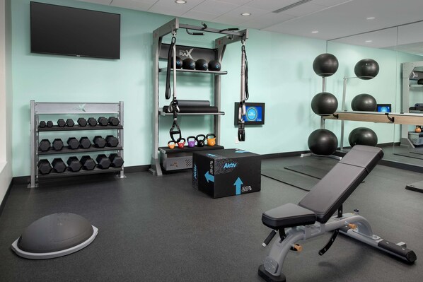 A gym with exercise equipment, dumbbells, and a treadmill.