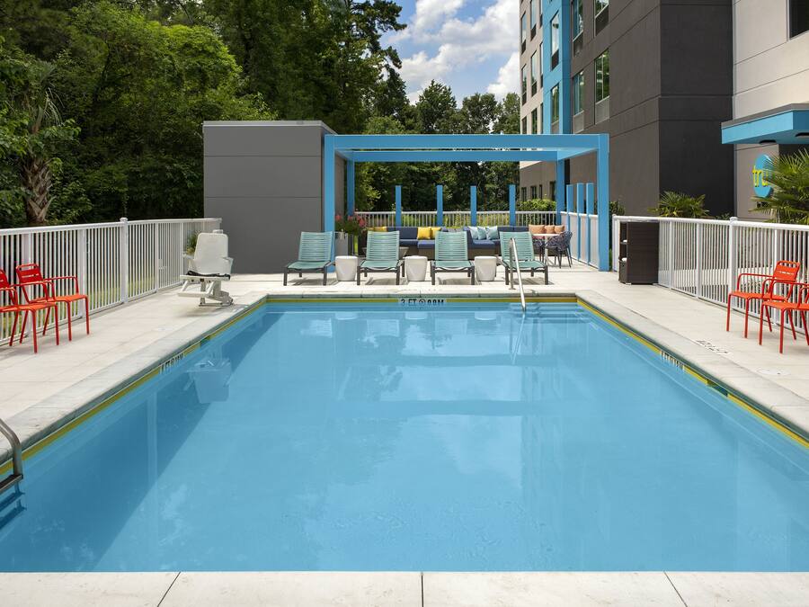 En swimmingpool med solstolar och ett avskärmat sittområde.