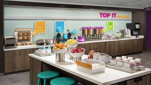 Een ontbijtbuffet met wafelijzers, schalen vol fruit en diverse ontbijtartikelen.